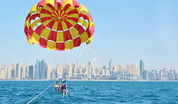 Family experiencing adventurous parasailing through the sky while towing behind a yacht near Jumeirah Beach in Dubai